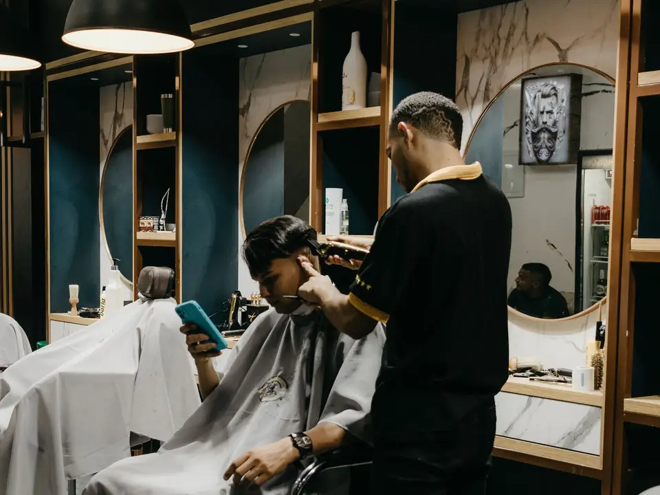 Barbero corta el cabello a un cliente en su barbería
