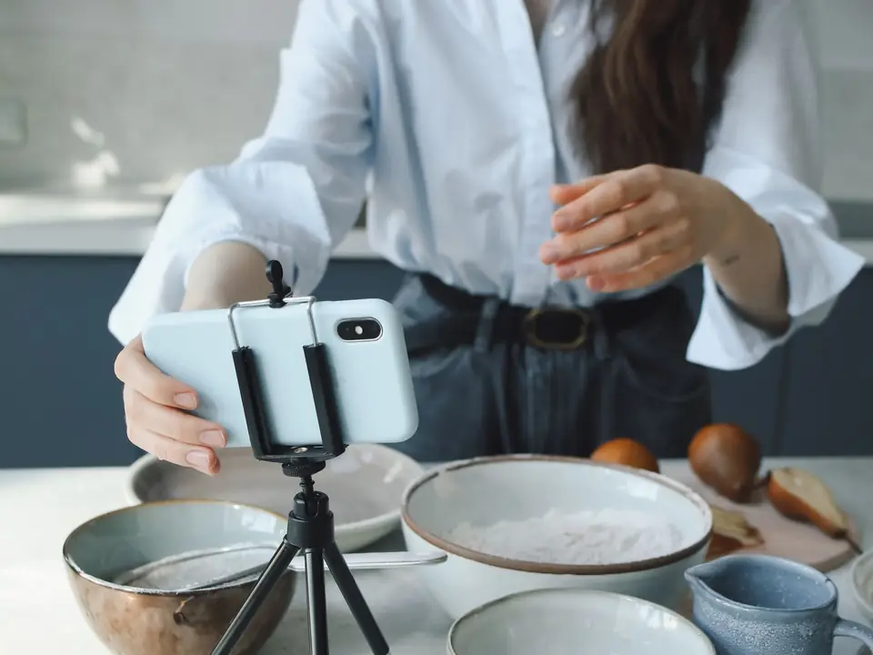Mujer graba un video de cocina con el teléfono en un trípode